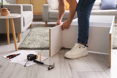 Genç adam, evde rafları monte ediyor.