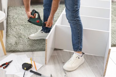 Delikanlı, evdeki rafların montajını yapıyor.