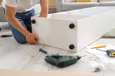 Evde döşeme raflarını monte eden genç bir adam.