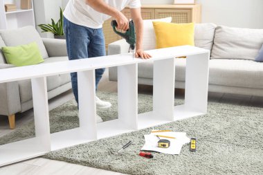 Evdeki halıda sondaj malzemesi monte eden genç adam.