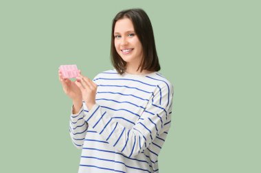 Yeşil arka planda hapları olan güzel bir kadın.