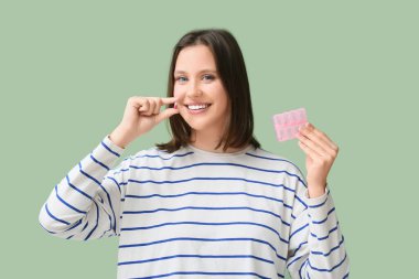 Yeşil arka planda hapları olan güzel bir kadın.