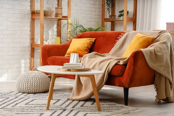 Oturma odasının içinde kırmızı kanepe, masa ve raf üniteleri var.