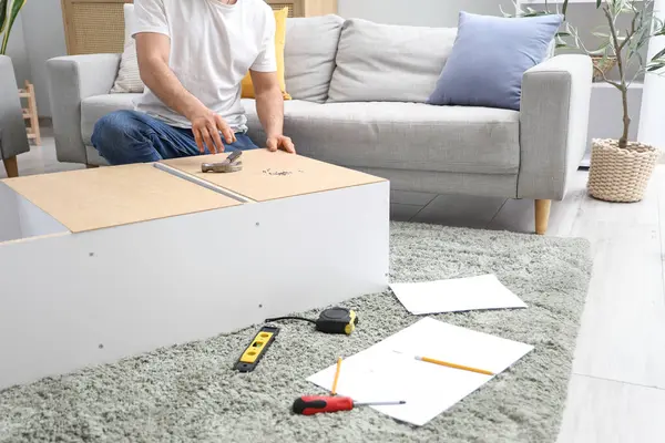 Genç adam evdeki halının üzerine raf monte ediyor.