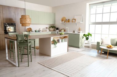 Beyaz mobilyaları ve ada masası olan modern mutfağın içi.