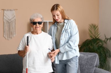 Kör büyükannesi evde el ele tutuşan genç bir kadın.