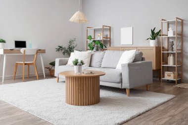 Masanın üzerinde kanepe, işyeri ve aroma spreyi olan oturma odası.