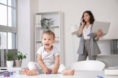 Annem ofiste çalışırken, küçük şirin bebek masada küplerle oynuyor.