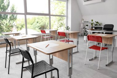 Modern sınıfta sınav için hazırlanmış sandalyeli okul masaları.