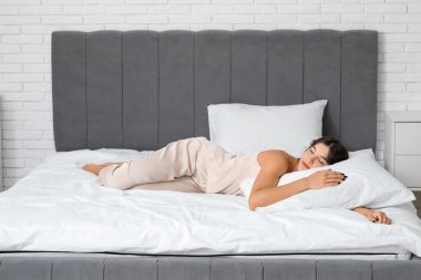 Genç bir kadın sabahları yatağında uyuyor.