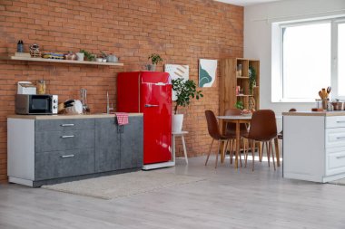 Kırmızı buzdolabı, tezgah ve yemek masası olan modern mutfak.