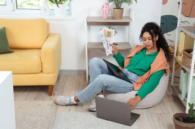 Ofisteki puf minder üzerinde grafik tabletle çalışan Afro-Amerikalı kadın web tasarımcısı