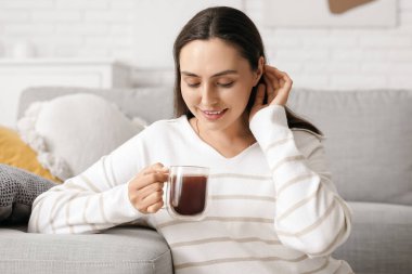Oturma odasında cam bardak sıcak kakaolu güzel bir kadın.