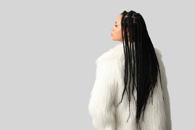 Beyaz arka planda örgüleri olan şık bir Afro-Amerikan kadın.