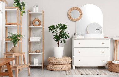 Lavabosu, çekmecesi ve rafları beyaz duvarın yanında olan şık bir banyo.