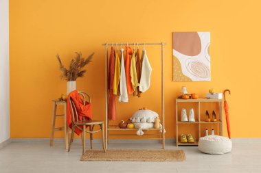 Sonbahar kıyafetleri, ayakkabıları ve balkabaklarıyla dolu bir oda.