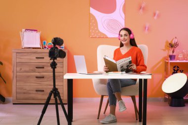 Kulaklıkları ve iç tasarım dergisi olan güzel genç bir kadın stüdyoda podcast yapıyor.