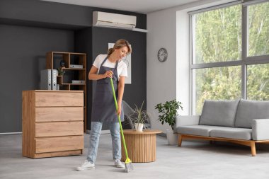 Kadın hademe ofisi temizliyor.