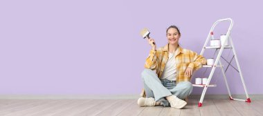 Leylak duvarının yanındaki merdiven üzerinde fırça ve boya kutuları olan genç bir kadın.