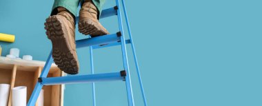 Mavi duvarın yanındaki merdivende işçi var, yakın plan. Tasarım için pankart