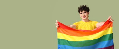 Yeşil arkaplanda LGBT bayrağı taşıyan genç transseksüel kadın.