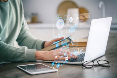 Dizüstü bilgisayarı ve not defteri olan erkek öğretmen evde online ders veriyor.
