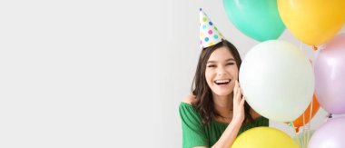 Balonlu güzel genç bir kadın açık arkaplanda doğum gününü kutluyor ve mesaj atmak için yeri var.