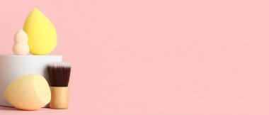 Makyaj süngerli dekoratif podyum ve pembe arka planda fırça