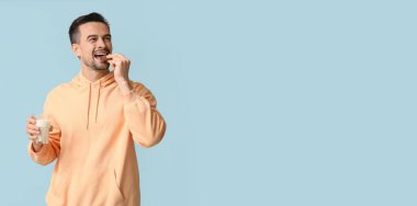 Yakışıklı adam açık mavi arkaplanda sütle lezzetli kurabiyeler yiyor.