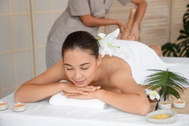 Çiçekli genç Asyalı kadın spa salonunda masaj yaptırıyor.