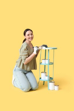 Sarı arka planda resim yapan genç bir kadın.