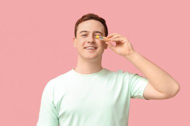 Pembe arka planda dudak merhemi olan mutlu genç bir adam.