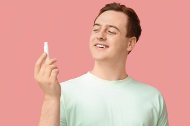 Pembe arka planda dudak merhemi olan mutlu genç bir adam.