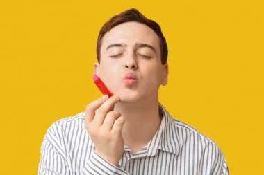 Sarı arka planda dudak merhemi olan yakışıklı bir genç.