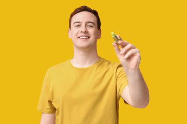 Sarı arka planda dudak merhemi olan yakışıklı bir genç.