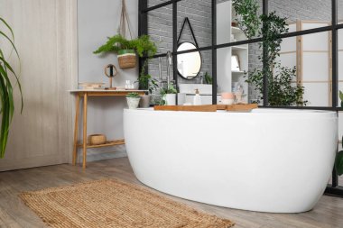 Banyo, seramik küvet, bitkiler ve katlanabilir ekran.