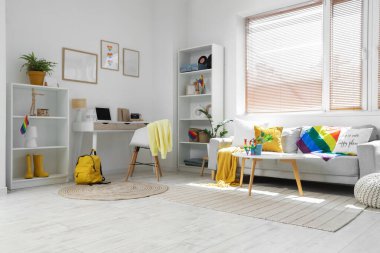 Kanepe, işyeri ve LGBT bayraklı aydınlık oturma odasının içi