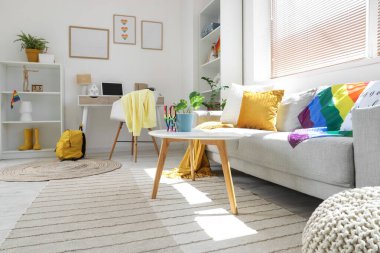 Kanepe, işyeri ve LGBT bayraklı aydınlık oturma odasının içi