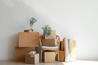 Kol sandalyesi, karton kutular ve odanın ışık duvarının yanındaki şeyler.