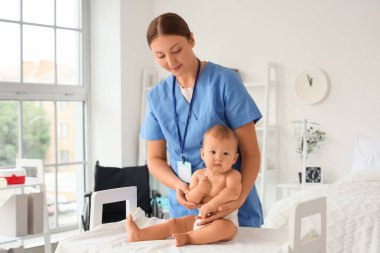 Doğum hastanesindeki masada yeni doğmuş bebeği olan genç hemşire.