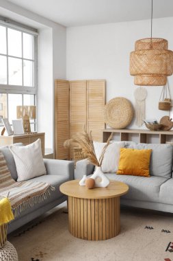 Gri kanepeleri ve pencerenin yanındaki kahve masası olan aydınlık oturma odasının içinde.