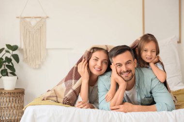 Küçük kız ve ailesi yatak odasında sıcak ekosenin altında yatıyor.