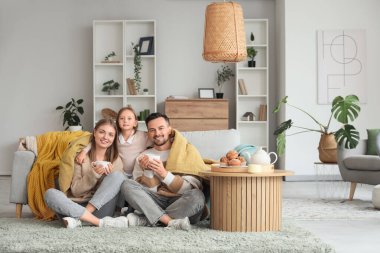 Küçük kız sıcak ekose kumaş ve çay eşliğinde ailesine sarılıyor.