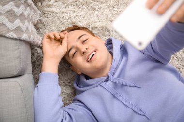 Cep telefonlu genç adam evde selfie çekiyor, yakın plan.