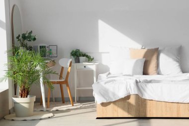 Makyaj masası ve bitkilerle aydınlık yatak odasının içinde.