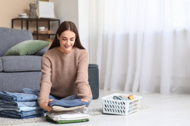 Genç bir kadın evde giysileri katlıyor.