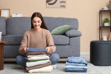 Genç bir kadın evde giysileri katlıyor.