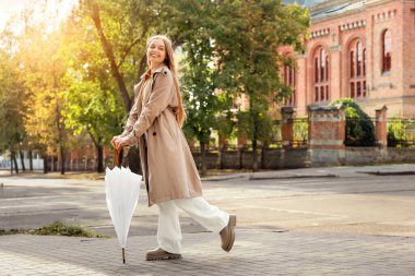 Şehir caddesinde şemsiyesi olan güzel genç bir kadın.