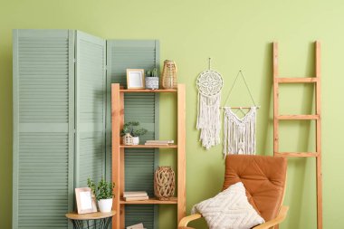 Yumuşak koltuk, raf ünitesi, sehpa ve güzel oturma odasının içindeki katlanır ekran.