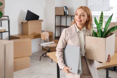 Taşındığı gün ofisinde kutu ve klasörü olan olgun bir iş kadını.